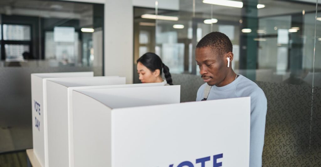 Two individuals casting votes in an indoor voting booth, emphasizing democracy.